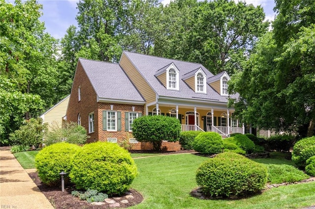 new england style home with covered porch, brick siding, roof with shingles, crawl space, and a front lawn