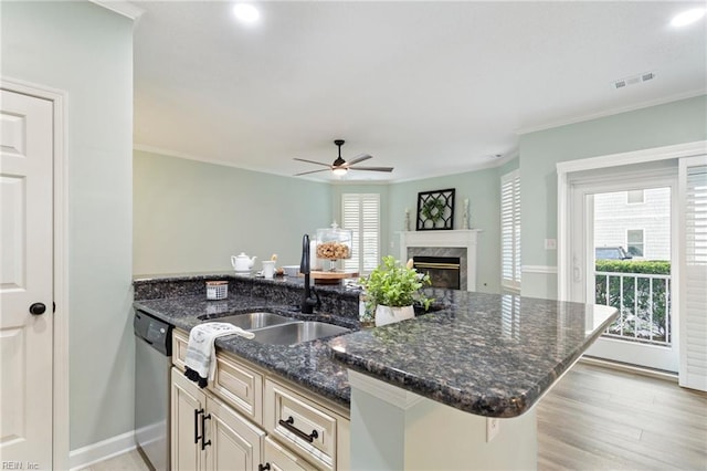 kitchen with visible vents, stainless steel dishwasher, a premium fireplace, a sink, and dark stone countertops