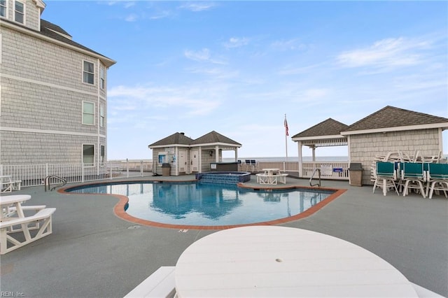 view of pool with a pool with connected hot tub, fence, a gazebo, and a patio