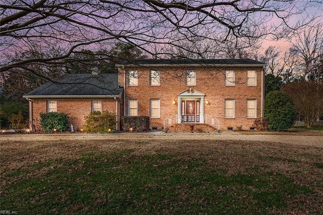 colonial home with crawl space, brick siding, and a yard