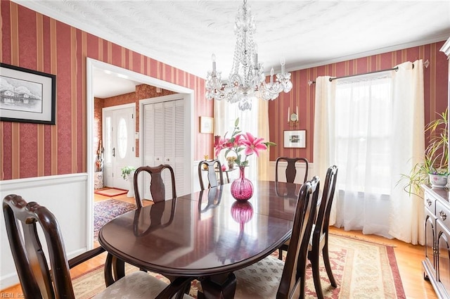 dining area with a notable chandelier, light wood finished floors, and wallpapered walls