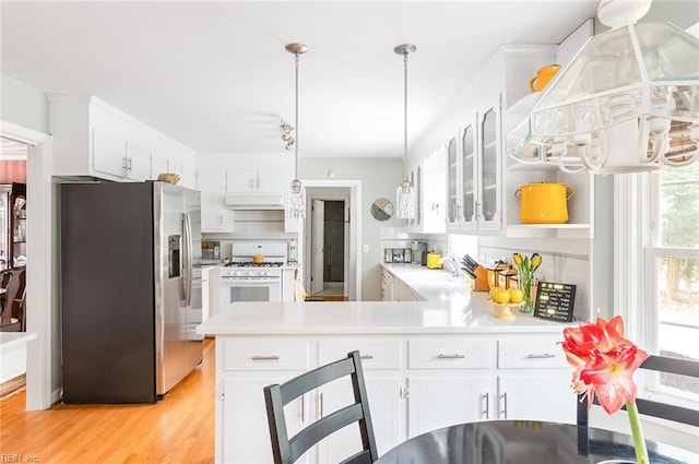 kitchen with white gas range oven, stainless steel refrigerator with ice dispenser, and white cabinets