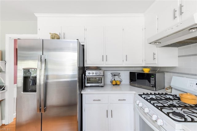 kitchen featuring under cabinet range hood, white cabinetry, light countertops, white gas range oven, and stainless steel fridge