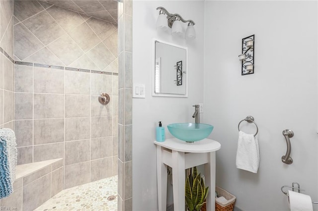 full bath featuring tiled shower and a sink