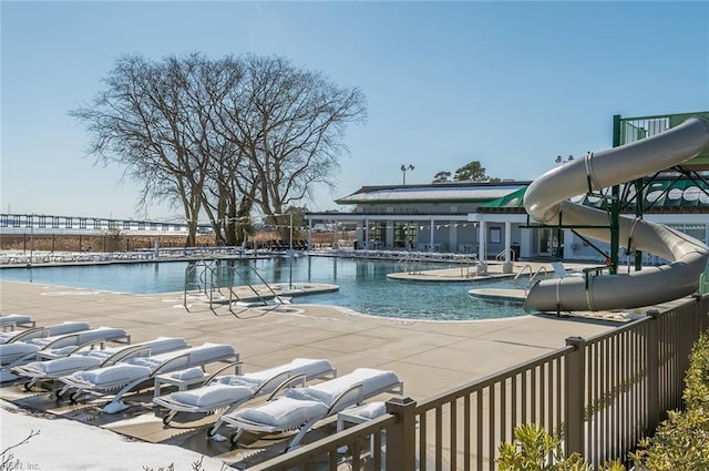 community pool featuring a patio, a water slide, and fence