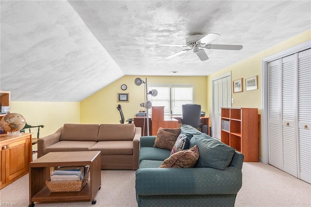 living room with ceiling fan, vaulted ceiling, a textured ceiling, and light colored carpet