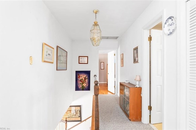 hallway featuring light carpet and a notable chandelier