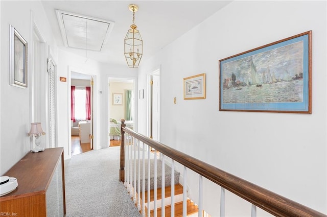 corridor with light carpet, attic access, and an upstairs landing