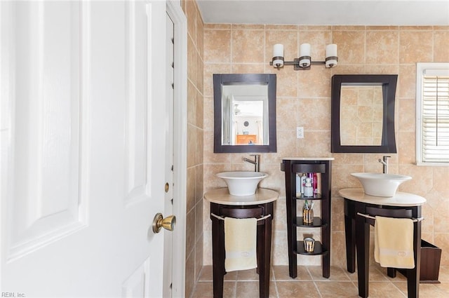 bathroom featuring two vanities, tile patterned flooring, a sink, and tile walls