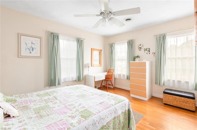 bedroom with ceiling fan, multiple windows, light wood-type flooring, and visible vents