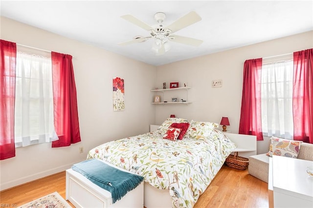 bedroom featuring ceiling fan, light wood-style flooring, and baseboards