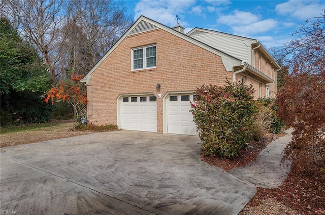 view of home's exterior featuring a garage, brick siding, and driveway