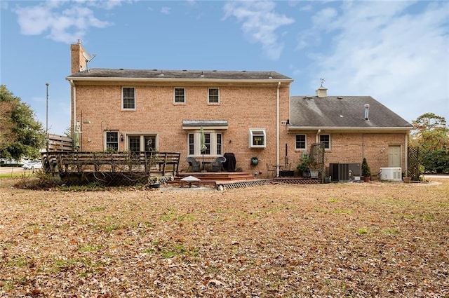 back of house featuring a yard, brick siding, a chimney, and a wooden deck