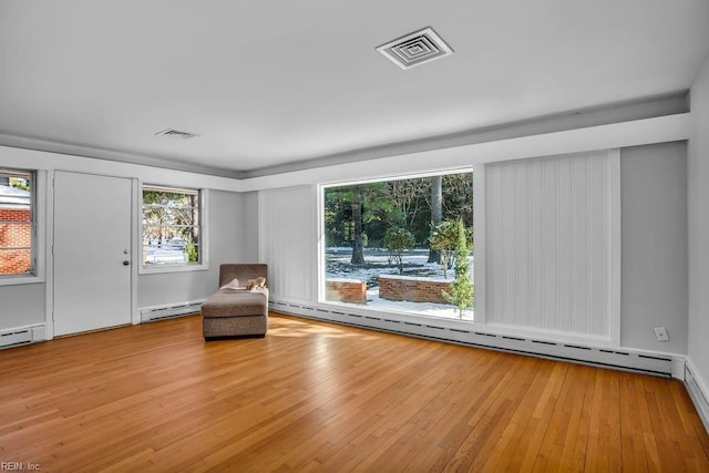 unfurnished room featuring a baseboard heating unit, light wood-type flooring, and visible vents