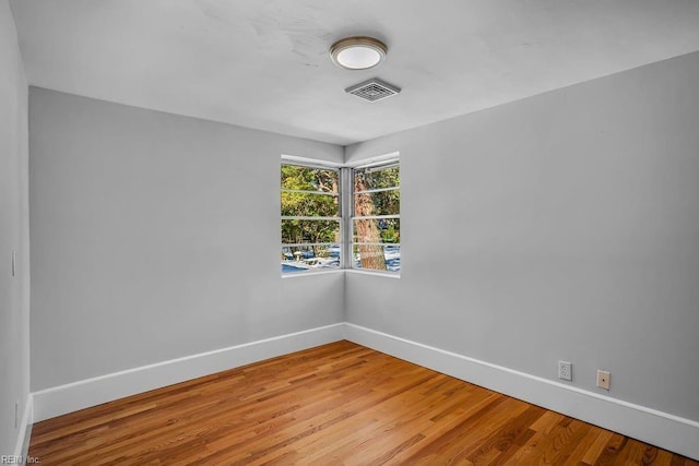 spare room featuring baseboards, visible vents, and wood finished floors