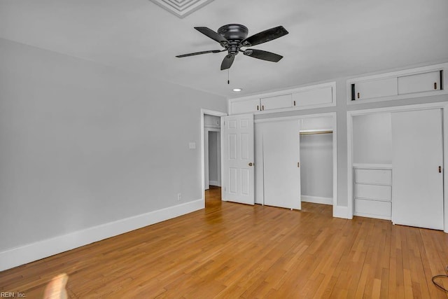 unfurnished bedroom featuring a ceiling fan, light wood-style flooring, baseboards, and two closets