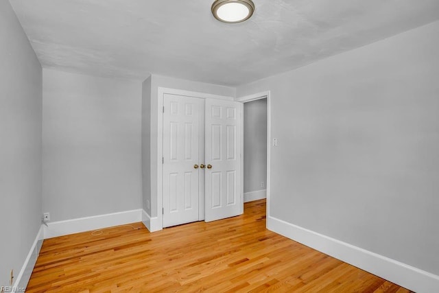 unfurnished bedroom with light wood-type flooring, baseboards, and a closet