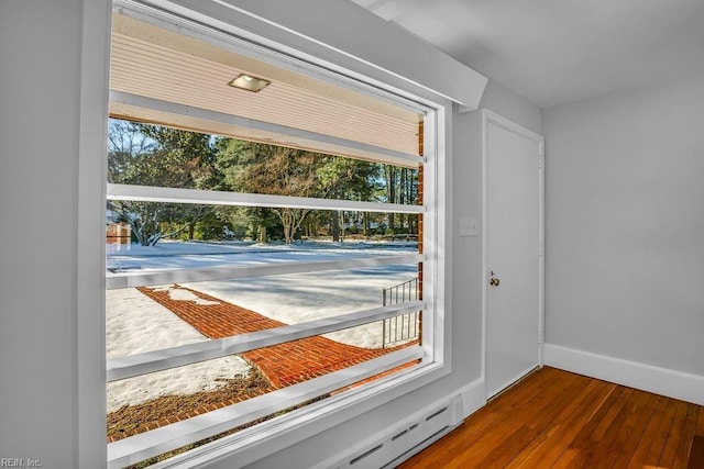 entryway featuring a baseboard heating unit, wood finished floors, and baseboards