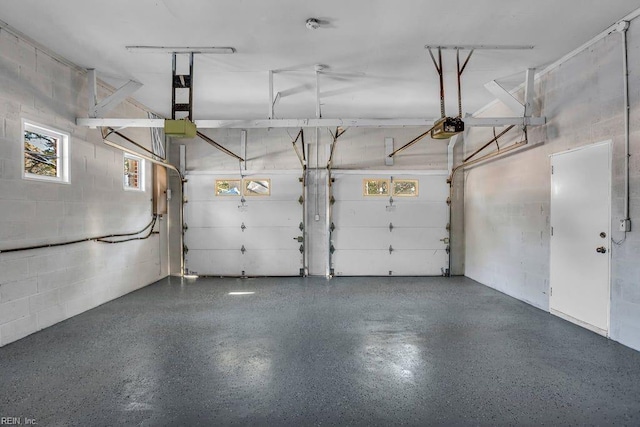 garage featuring concrete block wall and a garage door opener