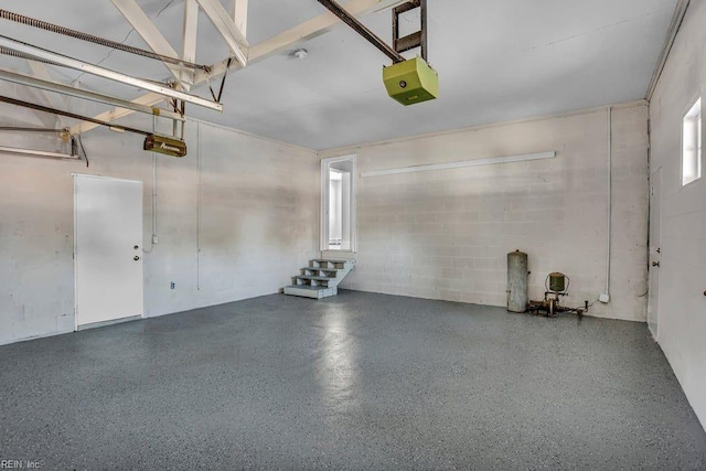 garage featuring concrete block wall and a garage door opener