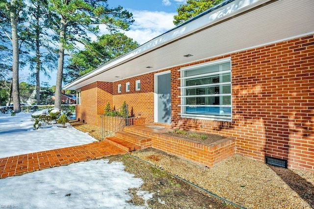 property entrance featuring crawl space, brick siding, and a patio