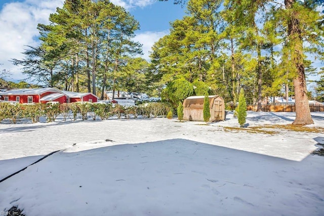 snowy yard featuring a storage unit and an outbuilding