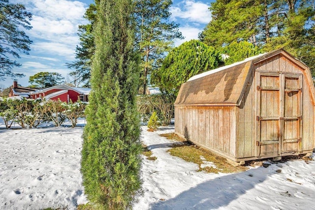 snow covered structure with an outbuilding