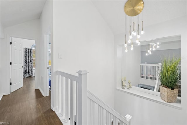 hallway featuring vaulted ceiling, dark wood-style flooring, and an upstairs landing