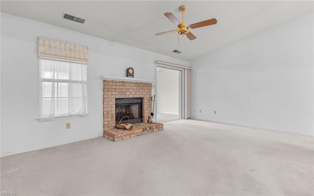 unfurnished living room featuring ceiling fan, lofted ceiling, carpet floors, a fireplace, and visible vents