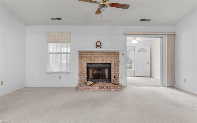 unfurnished living room with a healthy amount of sunlight, a fireplace, visible vents, and light colored carpet