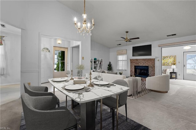 carpeted dining space featuring high vaulted ceiling, visible vents, a fireplace, and ceiling fan with notable chandelier