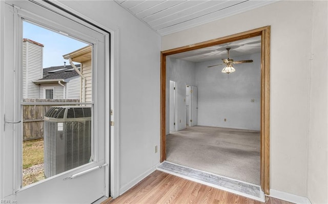 doorway to outside featuring light wood-style flooring, baseboards, and a ceiling fan