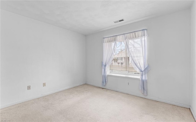 empty room featuring light carpet, visible vents, and baseboards