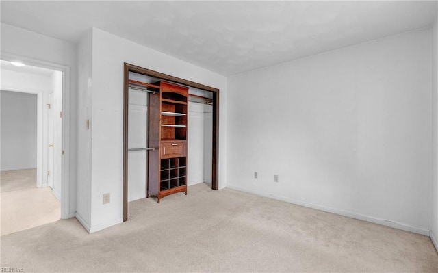 unfurnished bedroom featuring a closet, light colored carpet, and baseboards