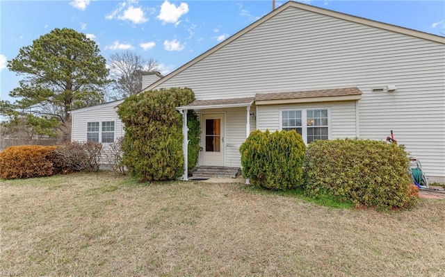 rear view of property with entry steps and a yard