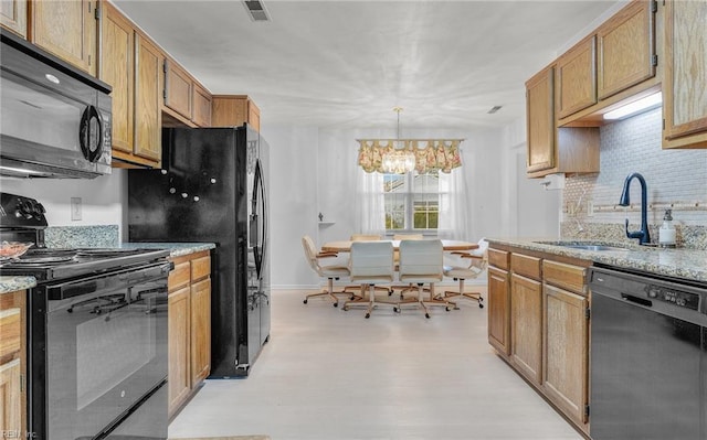 kitchen featuring tasteful backsplash, visible vents, light stone counters, black appliances, and a sink