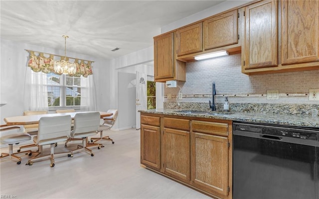 kitchen featuring dishwasher, backsplash, hanging light fixtures, light stone countertops, and a sink