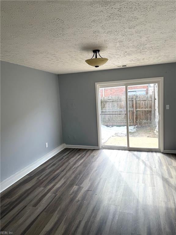 unfurnished room with dark wood-style floors, visible vents, baseboards, and a textured ceiling