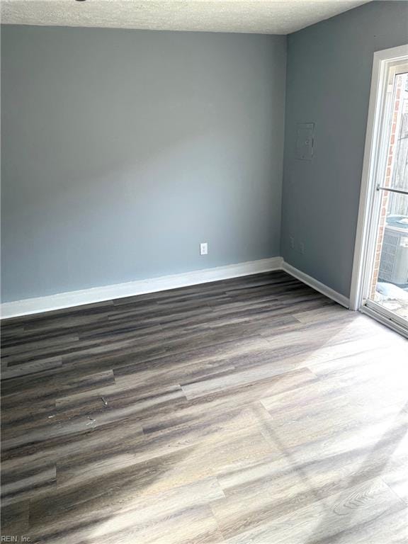 spare room featuring a textured ceiling, wood finished floors, and baseboards