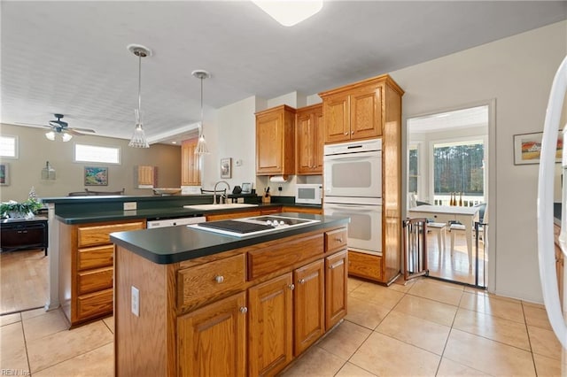 kitchen featuring dark countertops, white appliances, a sink, and a peninsula