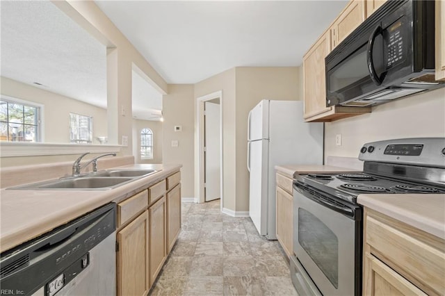 kitchen featuring light brown cabinets, a sink, baseboards, light countertops, and appliances with stainless steel finishes