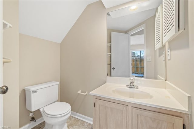 bathroom with lofted ceiling, vanity, toilet, and baseboards