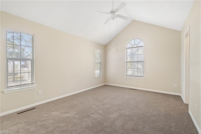 carpeted spare room featuring lofted ceiling, visible vents, a ceiling fan, a textured ceiling, and baseboards