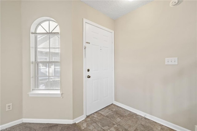 foyer entrance featuring baseboards and a textured ceiling