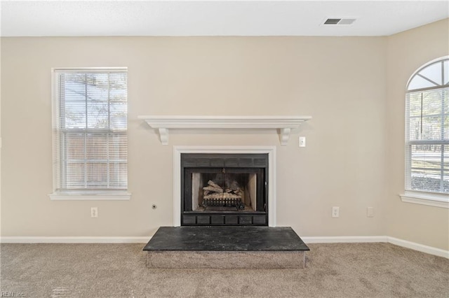 details with a fireplace with raised hearth, carpet, visible vents, and baseboards