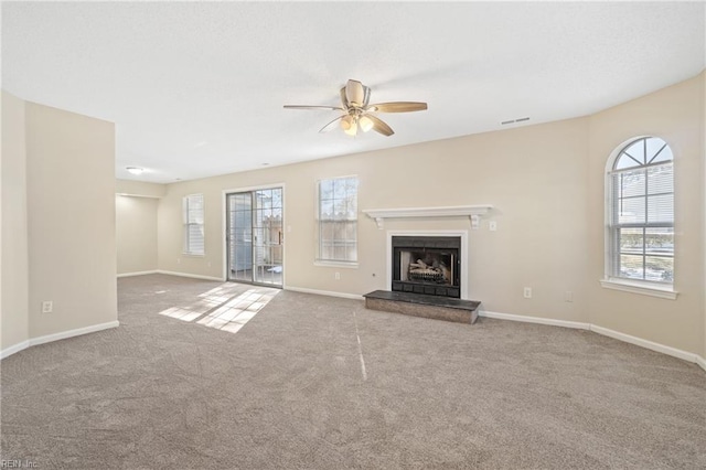 unfurnished living room with carpet flooring, visible vents, and a healthy amount of sunlight