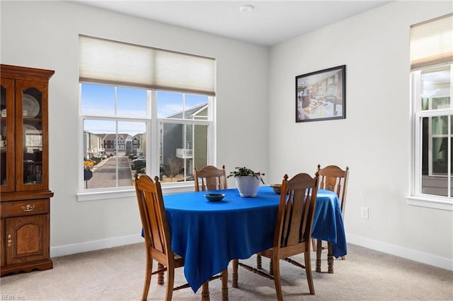 dining space featuring light carpet and baseboards