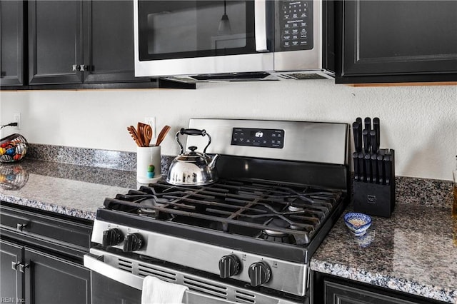 kitchen featuring appliances with stainless steel finishes, stone countertops, and dark cabinetry