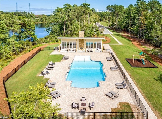 pool featuring a fenced backyard, a water view, playground community, a yard, and a patio area