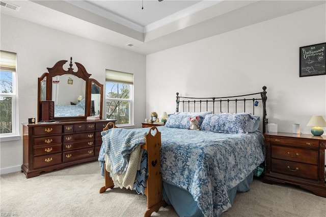 bedroom with baseboards, a raised ceiling, visible vents, and light colored carpet